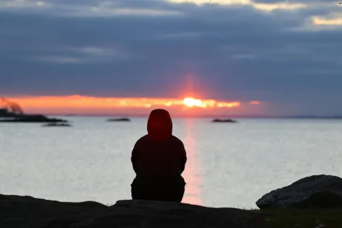 Person in Meditation auf einem Felsen im Sonnenuntergang