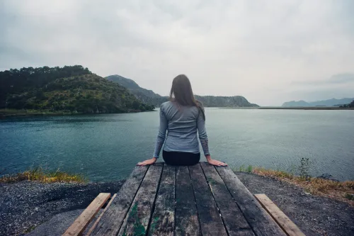 Person beim Meditieren am See